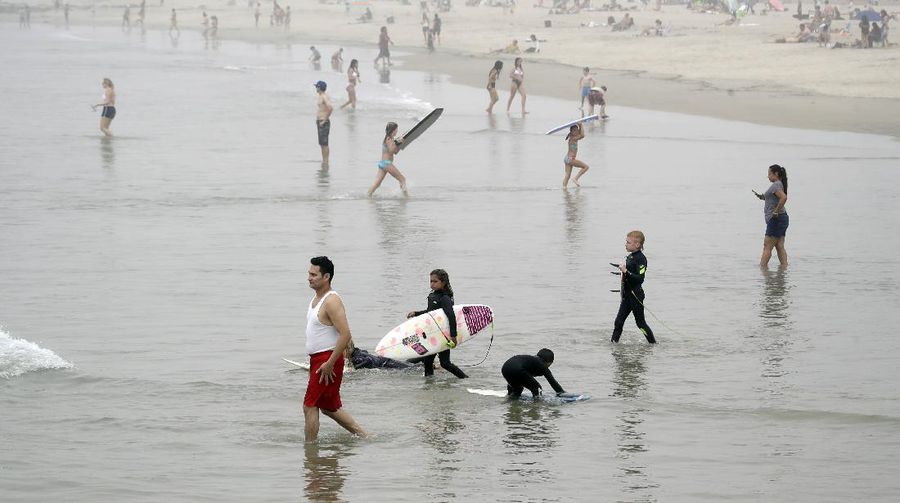 Warga Amerika Serikat berjalan-jalan di Pantai Huntington, California, meski sedang terjadi wabah virus corona. AP/Marcio Jose Sanchez