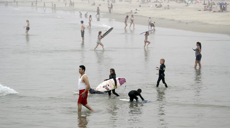 Warga Amerika Serikat berjalan-jalan di Pantai Huntington, California, meski sedang terjadi wabah virus corona. AP/Marcio Jose Sanchez