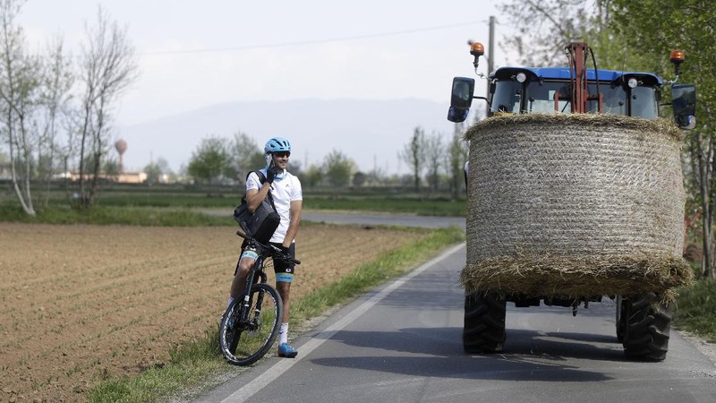 In this image taken on Tuesday, April 14, 2020, Italian professional cyclist Davide Martinelli, collects medicine at a pharmacy to be delivered to residents in Rovato, near Brescia, Northern Italy. There are no fans lining the road. No teammates providing support. And no race to win. Professional cyclist Davide Martinelli has achieved a moral victory, though, by using his bike to help deliver medicine to elderly residents of his hometown in northern Italy during the coronavirus pandemic. (AP Photo/Luca Bruno)