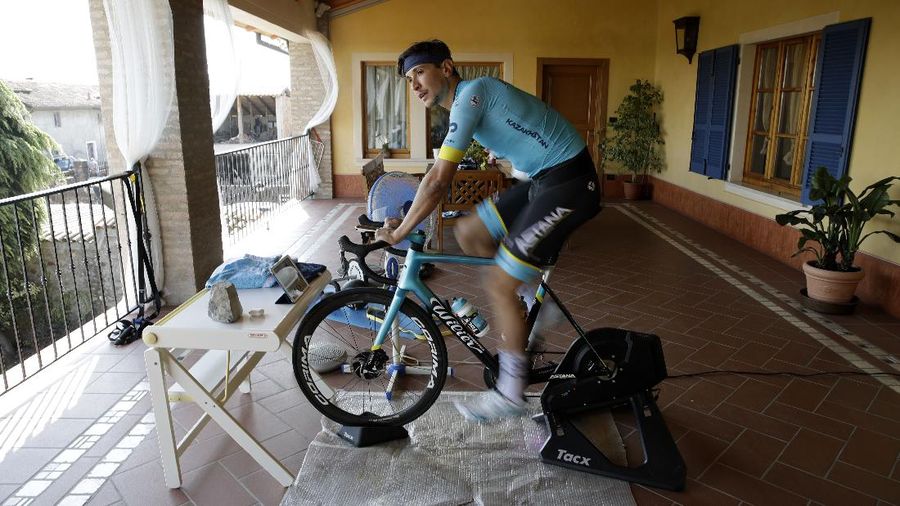 In this image taken on Tuesday, April 14, 2020, Italian professional cyclist Davide Martinelli, collects medicine at a pharmacy to be delivered to residents in Rovato, near Brescia, Northern Italy. There are no fans lining the road. No teammates providing support. And no race to win. Professional cyclist Davide Martinelli has achieved a moral victory, though, by using his bike to help deliver medicine to elderly residents of his hometown in northern Italy during the coronavirus pandemic. (AP Photo/Luca Bruno)