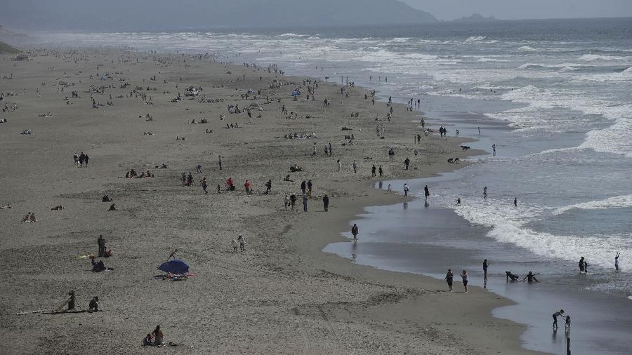 Warga Amerika Serikat berjalan-jalan di Pantai Huntington, California, meski sedang terjadi wabah virus corona. AP/Marcio Jose Sanchez