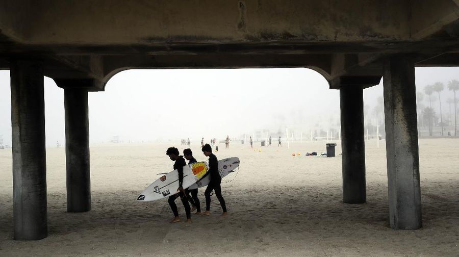 Warga Amerika Serikat berjalan-jalan di Pantai Huntington, California, meski sedang terjadi wabah virus corona. AP/Marcio Jose Sanchez