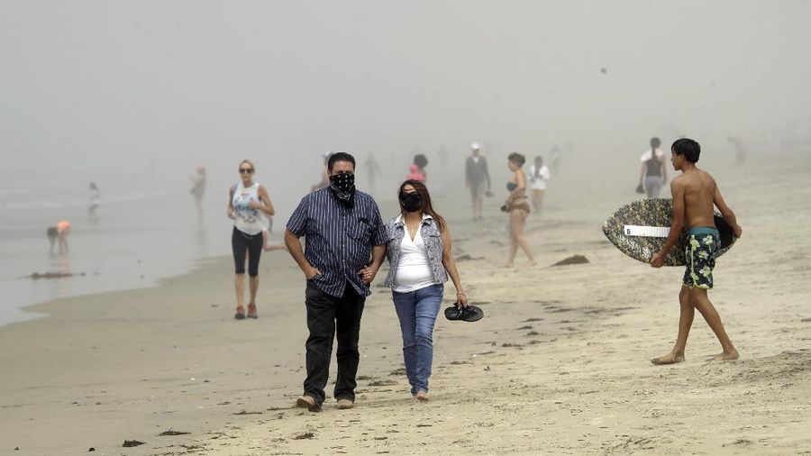 Warga Amerika Serikat berjalan-jalan di Pantai Huntington, California, meski sedang terjadi wabah virus corona. AP/Marcio Jose Sanchez