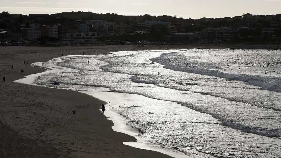A sign indicates the beach is closed as a surfers arrives for the 7A.M. opening of Bondi Beach in Sydney, Tuesday, April 28, 2020, as coronavirus pandemic restrictions are eased. The beach is open to swimmers and surfers to exercise only. (AP Photo/Rick Rycroft)