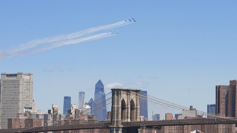 Workers stand on a dirt pile in Red Hook, N.Y., to view the Blue Angels and Thunderbirds flight teams flyover New York City skyline, Tuesday April 28, 2020, in New York. The flyover was in salute to first responders in the fight against the COVID-19 pandemic. (AP Photo/Bebeto Matthews)