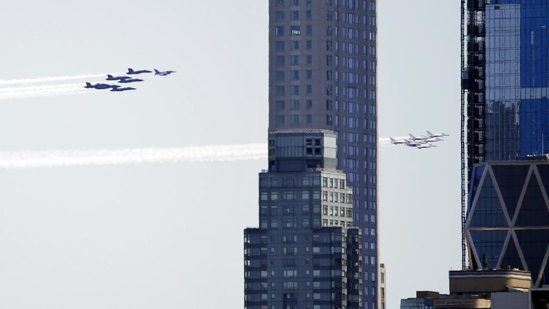 Workers stand on a dirt pile in Red Hook, N.Y., to view the Blue Angels and Thunderbirds flight teams flyover New York City skyline, Tuesday April 28, 2020, in New York. The flyover was in salute to first responders in the fight against the COVID-19 pandemic. (AP Photo/Bebeto Matthews)