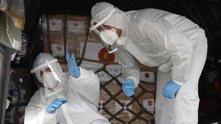Flight crew members stand on a tarmac in front of a donation of medical supplies from Turkey, Tuesday, April 28, 2020, at Andrews Air Force Base, Md. The donation to help fight the new coronavirus in the United States included surgical masks, sanitizers and protective suits. (AP Photo/Patrick Semansky)