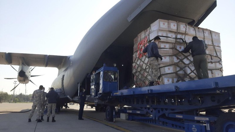 Flight crew members stand on a tarmac in front of a donation of medical supplies from Turkey, Tuesday, April 28, 2020, at Andrews Air Force Base, Md. The donation to help fight the new coronavirus in the United States included surgical masks, sanitizers and protective suits. (AP Photo/Patrick Semansky)