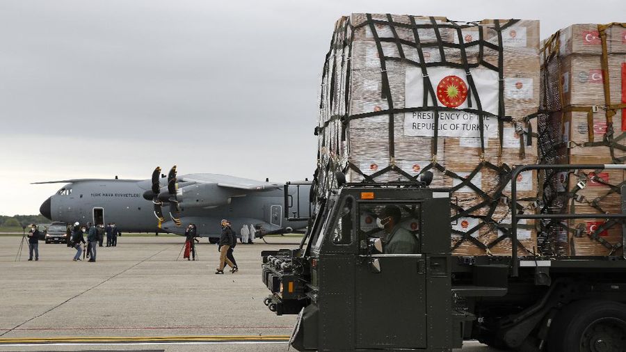 Flight crew members stand on a tarmac in front of a donation of medical supplies from Turkey, Tuesday, April 28, 2020, at Andrews Air Force Base, Md. The donation to help fight the new coronavirus in the United States included surgical masks, sanitizers and protective suits. (AP Photo/Patrick Semansky)