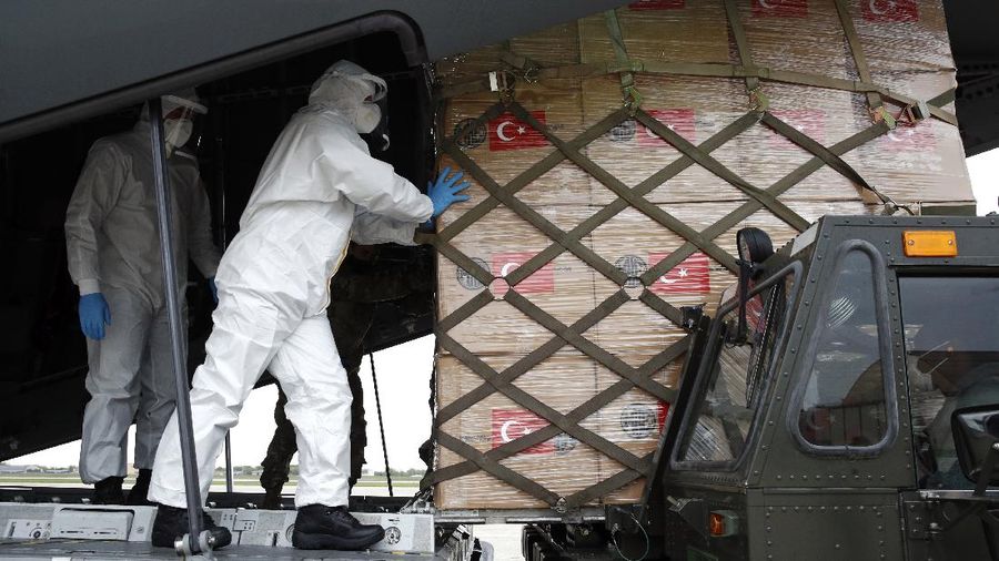 Flight crew members stand on a tarmac in front of a donation of medical supplies from Turkey, Tuesday, April 28, 2020, at Andrews Air Force Base, Md. The donation to help fight the new coronavirus in the United States included surgical masks, sanitizers and protective suits. (AP Photo/Patrick Semansky)