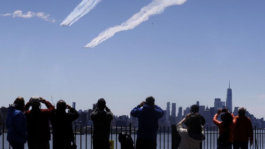 People watch as a formation of the Blue Angels and Thunderbirds flight teams pass in front of the New York City skyline as seen from Weehawken, N.J., Tuesday, April 28, 2020. The flyover was in salute to first responders in the fight against the new coronavirus. (AP Photo/Seth Wenig)