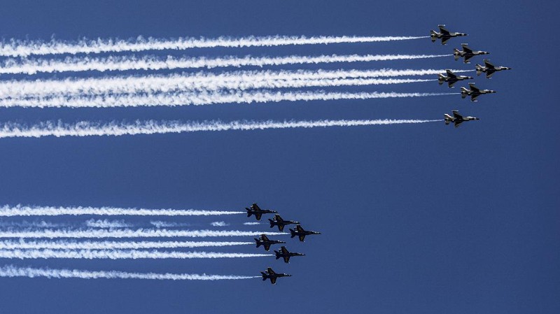 Workers stand on a dirt pile in Red Hook, N.Y., to view the Blue Angels and Thunderbirds flight teams flyover New York City skyline, Tuesday April 28, 2020, in New York. The flyover was in salute to first responders in the fight against the COVID-19 pandemic. (AP Photo/Bebeto Matthews)