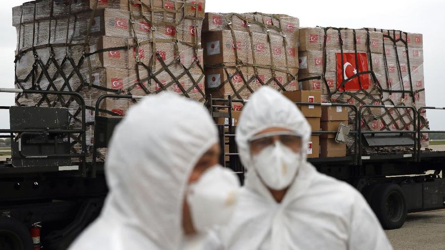 Flight crew members stand on a tarmac in front of a donation of medical supplies from Turkey, Tuesday, April 28, 2020, at Andrews Air Force Base, Md. The donation to help fight the new coronavirus in the United States included surgical masks, sanitizers and protective suits. (AP Photo/Patrick Semansky)