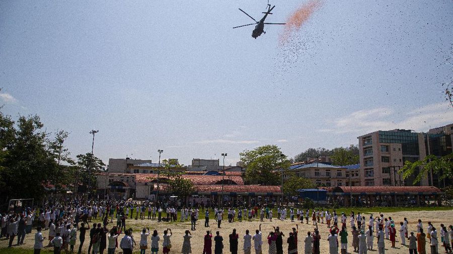 An Indian Air Force helicopter showers flower petals on health workers of Guwahati Medical College Hospital, (GMCH) in Gauhati, India, Sunday, May 3, 2020. The event was part of the Armed Forces' efforts to thank the workers, including doctors, nurses and police personnel, who have been at the forefront of the country's battle against the COVID-19 pandemic. (AP Photo/Anupam Nath)