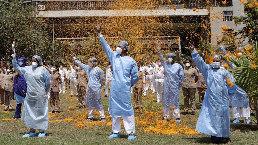 An Indian Air Force helicopter showers flower petals on health workers of Guwahati Medical College Hospital, (GMCH) in Gauhati, India, Sunday, May 3, 2020. The event was part of the Armed Forces' efforts to thank the workers, including doctors, nurses and police personnel, who have been at the forefront of the country's battle against the COVID-19 pandemic. (AP Photo/Anupam Nath)