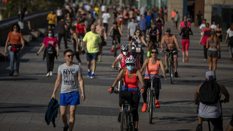 People exercise on a seafront promenade in Barcelona, Spain, Sunday, May 3, 2020. Spaniards have filled the streets of the country to do exercise after seven weeks of confinement to their homes to fight the coronavirus pandemic. People ran, walked, or rode bicycles under a brilliant sunny sky in Barcelona on Saturday, where many flocked to the maritime promenade to get as close as possible to the still off-limits beach. (AP Photo/Emilio Morenatti)