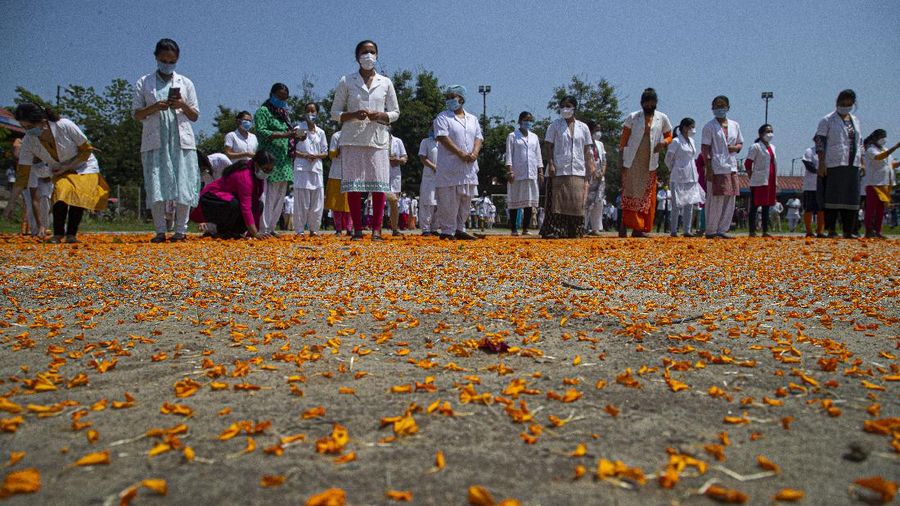 An Indian Air Force helicopter showers flower petals on health workers of Guwahati Medical College Hospital, (GMCH) in Gauhati, India, Sunday, May 3, 2020. The event was part of the Armed Forces' efforts to thank the workers, including doctors, nurses and police personnel, who have been at the forefront of the country's battle against the COVID-19 pandemic. (AP Photo/Anupam Nath)