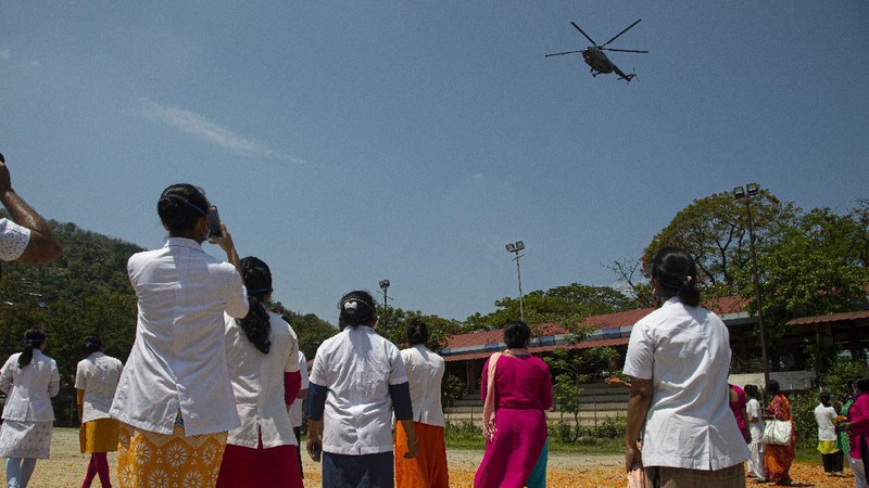 An Indian Air Force helicopter showers flower petals on health workers of Guwahati Medical College Hospital, (GMCH) in Gauhati, India, Sunday, May 3, 2020. The event was part of the Armed Forces' efforts to thank the workers, including doctors, nurses and police personnel, who have been at the forefront of the country's battle against the COVID-19 pandemic. (AP Photo/Anupam Nath)