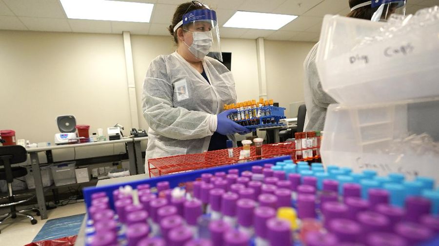 Julie Janke, a medical technologist at Principle Health Systems and SynerGene Laboratory, helps sort samples for different tests Tuesday, April 28, 2020, in Houston. The company, which opened two new testing locations Tuesday, is now offering a new COVID-19 antibody test developed by Abbott Laboratories. (AP Photo/David J. Phillip)