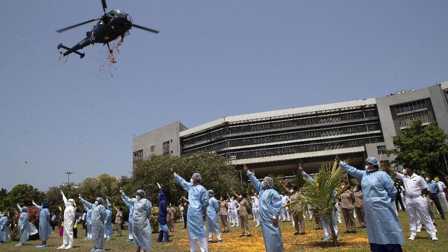 An Indian Air Force helicopter showers flower petals on health workers of Guwahati Medical College Hospital, (GMCH) in Gauhati, India, Sunday, May 3, 2020. The event was part of the Armed Forces' efforts to thank the workers, including doctors, nurses and police personnel, who have been at the forefront of the country's battle against the COVID-19 pandemic. (AP Photo/Anupam Nath)