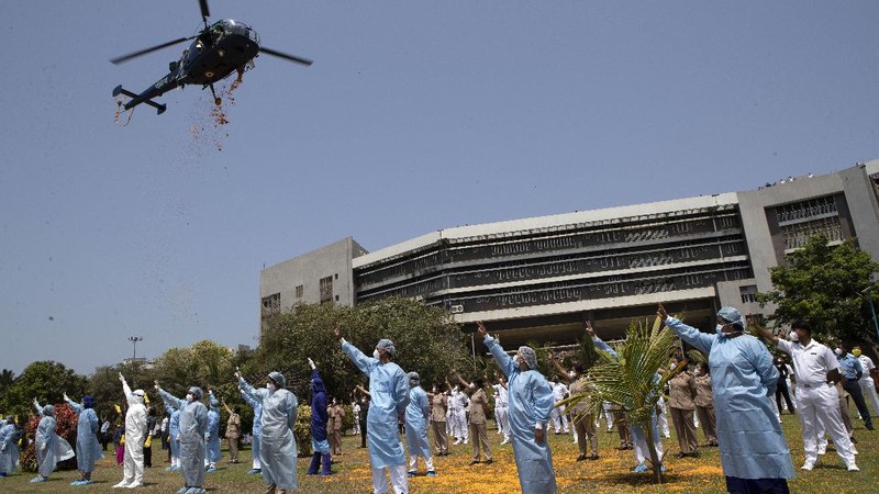 An Indian Air Force helicopter showers flower petals on health workers of Guwahati Medical College Hospital, (GMCH) in Gauhati, India, Sunday, May 3, 2020. The event was part of the Armed Forces' efforts to thank the workers, including doctors, nurses and police personnel, who have been at the forefront of the country's battle against the COVID-19 pandemic. (AP Photo/Anupam Nath)