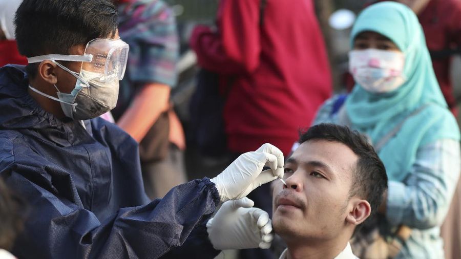A health worker conducts a swab test for the new coronavirus in Bekasi on the outskirts of Jakarta, Indonesia, Tuesday, May 5, 2020. (AP Photo/Achmad Ibrahim)