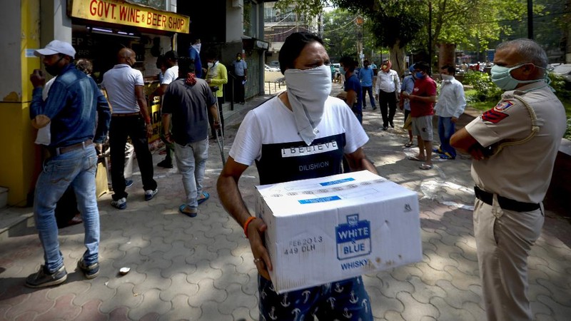 Indians line up to buy liquor outside one of the liquor shops which was reopened Monday after six weeks lockdown on the outskirts of New Delhi, India, Monday, May 4, 2020. India's six-week coronavirus lockdown, which was supposed to end on Monday, has been extended for another two weeks, with a few relaxations. Locking down the country's 1.3 billion people has slowed down the spread of the virus, but has come at the enormous cost of upending lives and millions of lost jobs. (AP Photo/Altaf Qadri)