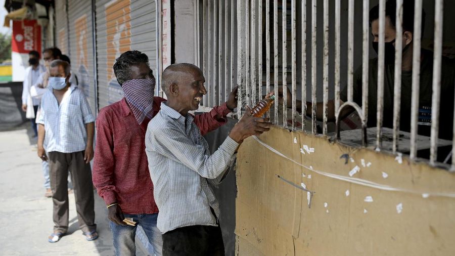 Indians line up to buy liquor outside one of the liquor shops which was reopened Monday after six weeks lockdown on the outskirts of New Delhi, India, Monday, May 4, 2020. India's six-week coronavirus lockdown, which was supposed to end on Monday, has been extended for another two weeks, with a few relaxations. Locking down the country's 1.3 billion people has slowed down the spread of the virus, but has come at the enormous cost of upending lives and millions of lost jobs. (AP Photo/Altaf Qadri)