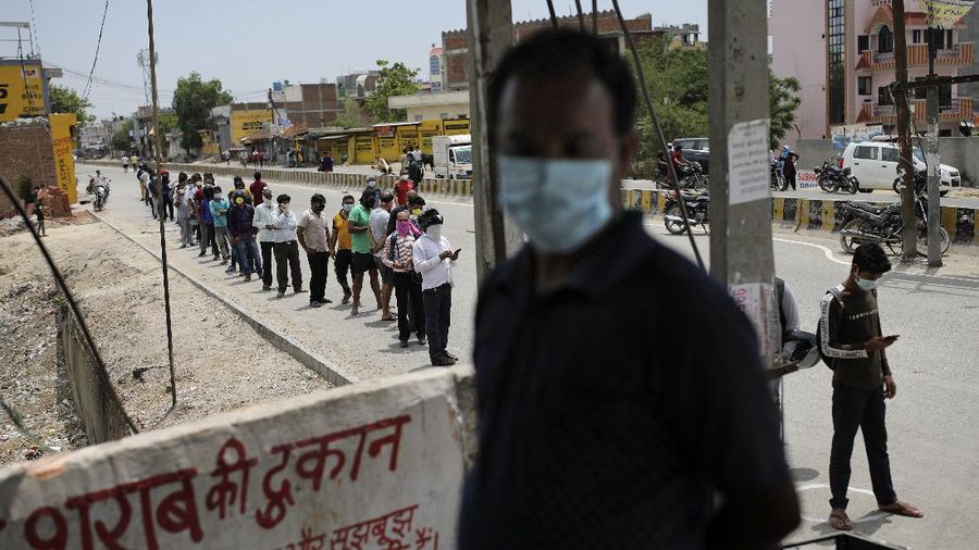 Indians line up to buy liquor outside one of the liquor shops which was reopened Monday after six weeks lockdown on the outskirts of New Delhi, India, Monday, May 4, 2020. India's six-week coronavirus lockdown, which was supposed to end on Monday, has been extended for another two weeks, with a few relaxations. Locking down the country's 1.3 billion people has slowed down the spread of the virus, but has come at the enormous cost of upending lives and millions of lost jobs. (AP Photo/Altaf Qadri)