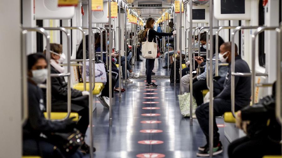Commuters sit in the subway in Milan, Italy, Monday, May 4, 2020.  Marks on the floor show the correct distance to be kept. Italy began stirring again Monday after a two-month coronavirus shutdown, with 4.4 million Italians able to return to work and restrictions on movement eased in the first European country to lock down in a bid to stem COVID-19 infections. (Claudio Furlan/LaPresse via AP)