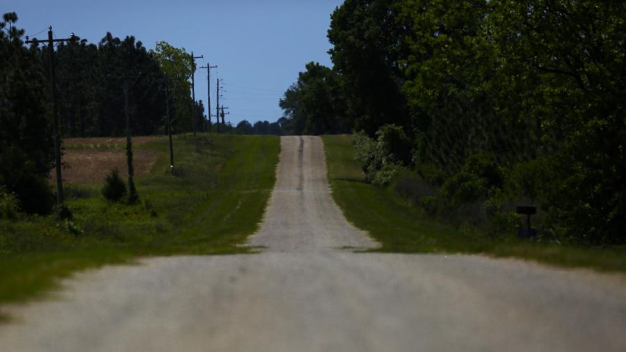 An empty road leading towards a rural countryside of Dawson, Ga., is seen on Friday, April 17, 2020, in Dawson, Ga. Of the 20 counties with the highest death rate in America, six of them are in rural southwest Georgia, where there are no packed skyrise apartment buildings or subways. Other out-of-the way places so far unscathed by the pandemic might believe, like many in Dawson once did, that the virus won't find them out there. But ambulances rushed along country roads, fields and farms in either direction, carrying COVID-19 patients to the nearest hospital, for some an hour away. (AP Photo/Brynn Anderson)