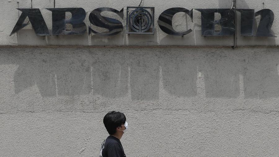 A man wearing a mask passes by the headquarters of broadcast network ABS-CBN Corp. on Wednesday May 6, 2020 in Manila, Philippines. Philippine church and business leaders expressed alarm Wednesday over a government agency’s shutdown of the country’s largest TV and radio network, which has been a major provider of news on the coronavirus pandemic. (AP Photo/Aaron Favila)
