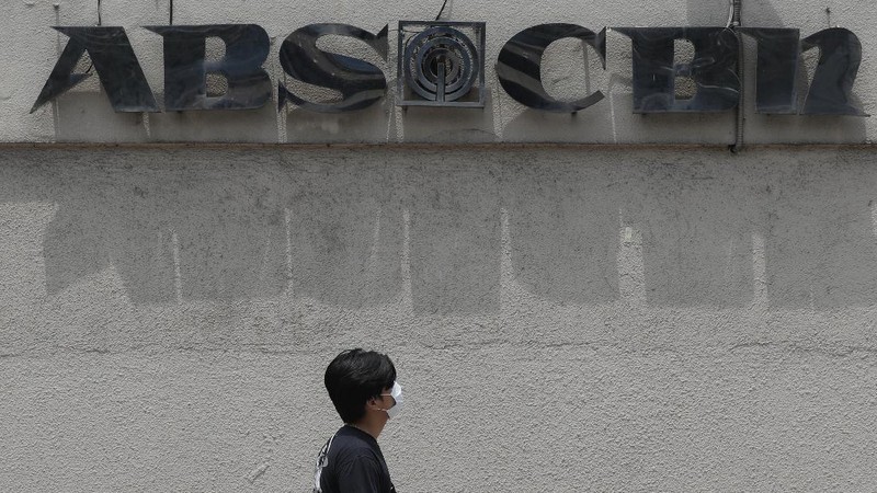 A man wearing a mask passes by the headquarters of broadcast network ABS-CBN Corp. on Wednesday May 6, 2020 in Manila, Philippines. Philippine church and business leaders expressed alarm Wednesday over a government agency’s shutdown of the country’s largest TV and radio network, which has been a major provider of news on the coronavirus pandemic. (AP Photo/Aaron Favila)