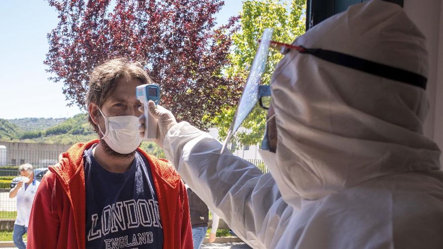 A worker of the Calzaturificio M.G.T shoe factory in Castelnuovo Vomano, central Italy, has his temperature checked at the entrance of the factory upon his returns to work, Monday, May 4, 2020. Italy began stirring again Monday after a two-month coronavirus shutdown, with 4.4 million Italians able to return to work and restrictions on movement eased in the first European country to lock down in a bid to stem COVID-19 infections. (AP Photo/Domenico Stinellis)