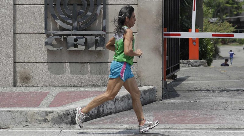 A man wearing a mask passes by the headquarters of broadcast network ABS-CBN Corp. on Wednesday May 6, 2020 in Manila, Philippines. Philippine church and business leaders expressed alarm Wednesday over a government agency’s shutdown of the country’s largest TV and radio network, which has been a major provider of news on the coronavirus pandemic. (AP Photo/Aaron Favila)