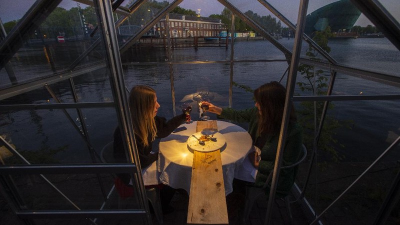Staff at the Mediamatic restaurant serve food to volunteers seated in small glasshouses during a try-out of a setup which respects social distancing abiding by government directives to combat the spread of the COVID-19 coronavirus in Amsterdam, Netherlands, Tuesday, May 5, 2020. (AP Photo/Peter Dejong)