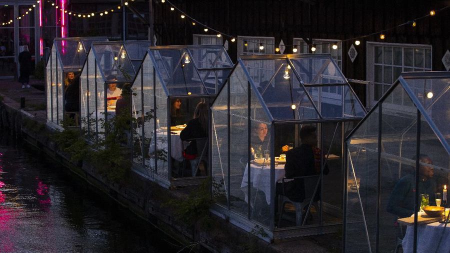 Staff at the Mediamatic restaurant serve food to volunteers seated in small glasshouses during a try-out of a setup which respects social distancing abiding by government directives to combat the spread of the COVID-19 coronavirus in Amsterdam, Netherlands, Tuesday, May 5, 2020. (AP Photo/Peter Dejong)