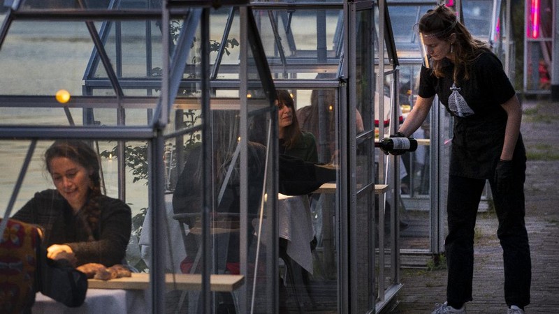Staff at the Mediamatic restaurant serve food to volunteers seated in small glasshouses during a try-out of a setup which respects social distancing abiding by government directives to combat the spread of the COVID-19 coronavirus in Amsterdam, Netherlands, Tuesday, May 5, 2020. (AP Photo/Peter Dejong)