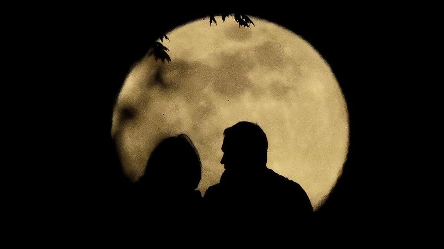 A couple watches the full moon rise Wednesday, May 6, 2020, from a park in Kansas City, Mo. (AP Photo/Charlie Riedel)