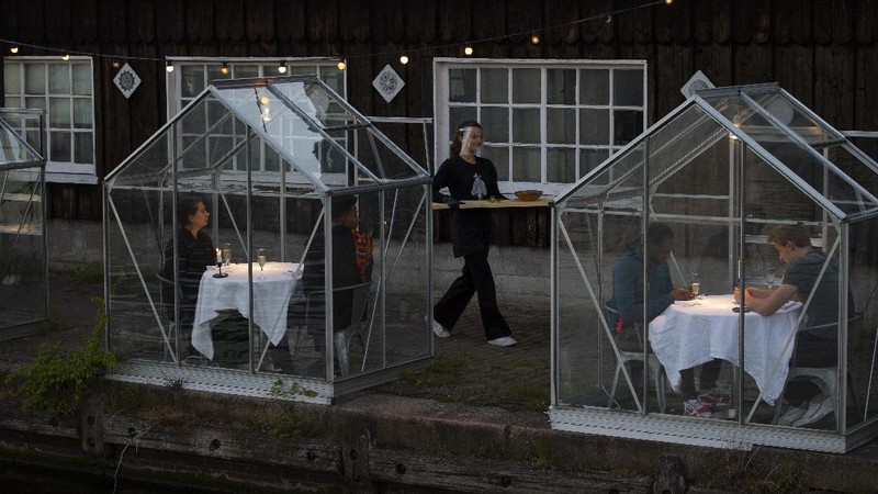 Staff at the Mediamatic restaurant serve food to volunteers seated in small glasshouses during a try-out of a setup which respects social distancing abiding by government directives to combat the spread of the COVID-19 coronavirus in Amsterdam, Netherlands, Tuesday, May 5, 2020. (AP Photo/Peter Dejong)