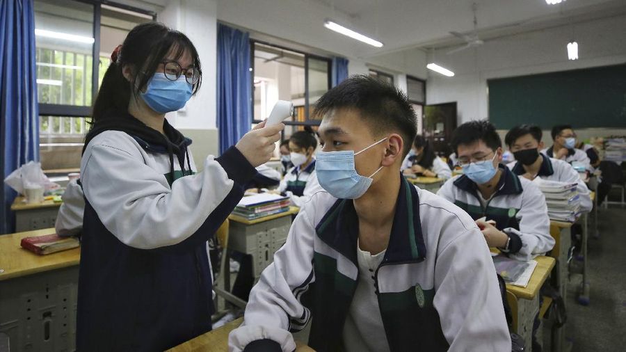 Students wearing protective face masks to help curb the spread of the new coronavirus walk in social distancing as they arrive to a high school in Wuhan in central China's Hubei province, Wednesday, May 6, 2020. Senior students returned to classes on Wednesday in the central Chinese city of Wuhan, the epicenter of the coronavirus pandemic, after no new cases or deaths were reported from the outbreak that had prompted a 76-day quarantine in the city of 11 million. (Chinatopix via AP)