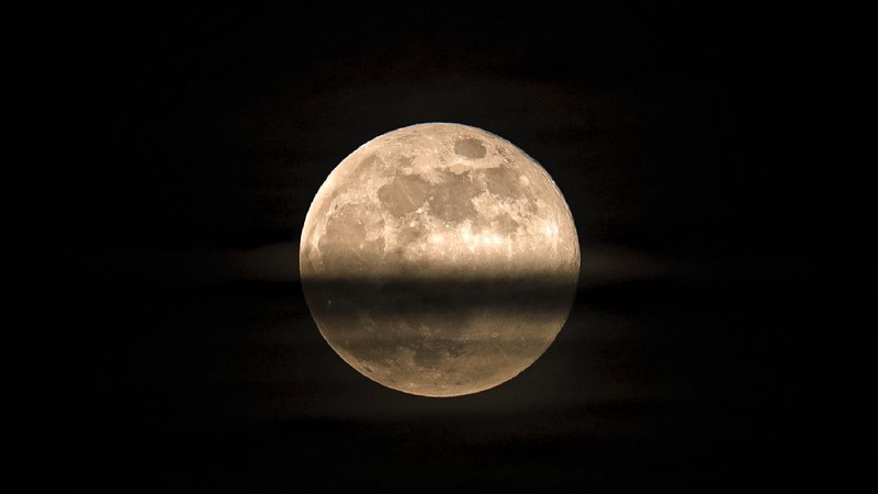 A couple watches the full moon rise Wednesday, May 6, 2020, from a park in Kansas City, Mo. (AP Photo/Charlie Riedel)