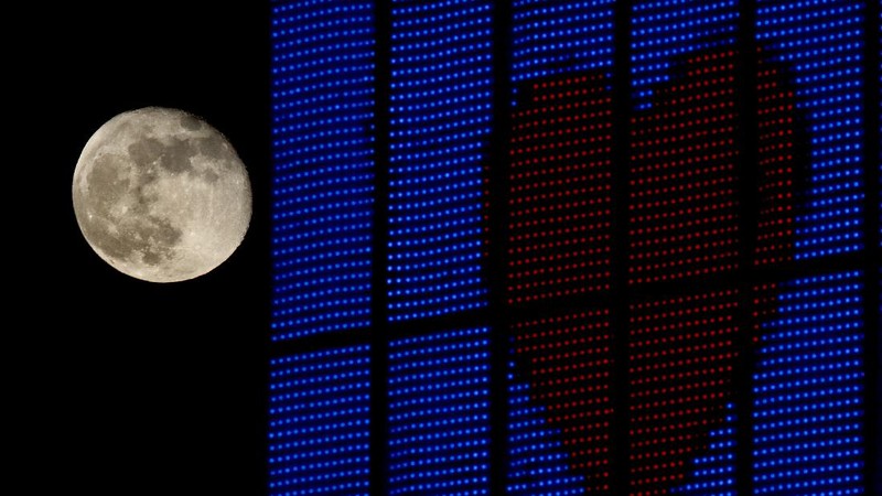 A couple watches the full moon rise Wednesday, May 6, 2020, from a park in Kansas City, Mo. (AP Photo/Charlie Riedel)