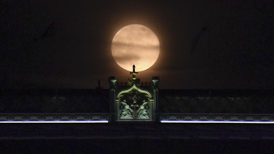 A couple watches the full moon rise Wednesday, May 6, 2020, from a park in Kansas City, Mo. (AP Photo/Charlie Riedel)
