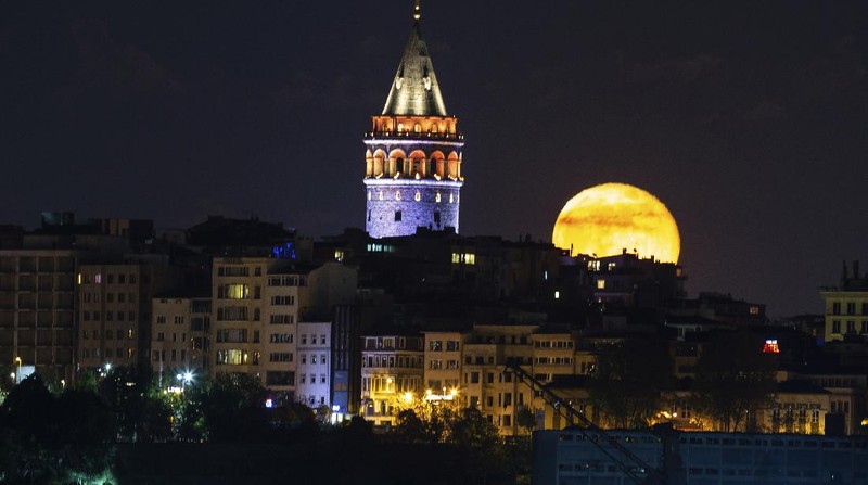 A couple watches the full moon rise Wednesday, May 6, 2020, from a park in Kansas City, Mo. (AP Photo/Charlie Riedel)