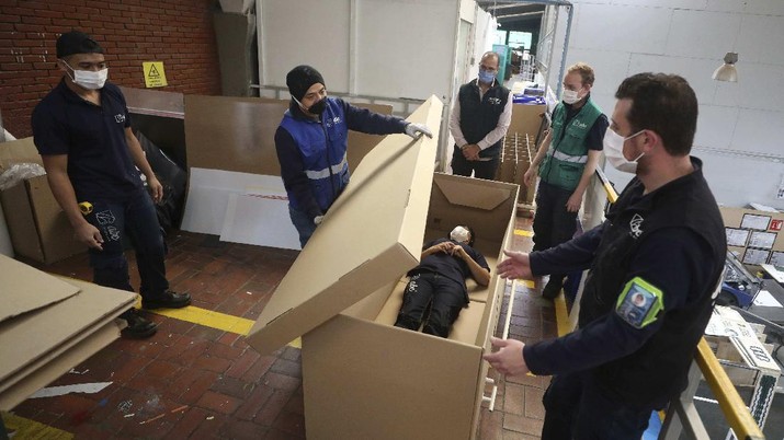 A worker at a company that designs packaging for product displays assembles a cardboard box designed to serve as both a hospital bed and a coffin, intended for COVID-19 patients, in Bogota, Colombia, Friday, May 8, 2020. Owner Rodolfo Gomez said he plans to donate the first units to Colombia's Amazonas state, and that the company will sell others to small hospitals for 87 dollars. (AP Photo/Fernando Vergara)
