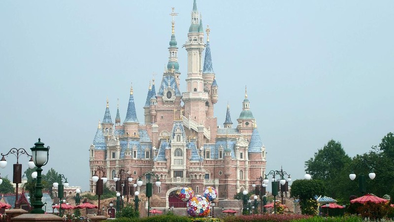 Visitors, wearing face masks, wait to enter the Disneyland theme park in Shanghai as it reopened, Monday, May 11, 2020. Visits will be limited initially and must be booked in advance, and the company said it will increase cleaning and require social distancing in lines for the various attractions. With warmer weather and new coronavirus cases and deaths falling to near-zero, China has been reopening tourist sites such as the Great Wall and the Forbidden City palace complex in Beijing.(AP Photo/Sam McNeil)