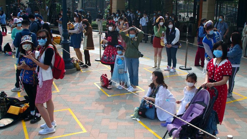Visitors, wearing face masks, wait to enter the Disneyland theme park in Shanghai as it reopened, Monday, May 11, 2020. Visits will be limited initially and must be booked in advance, and the company said it will increase cleaning and require social distancing in lines for the various attractions. With warmer weather and new coronavirus cases and deaths falling to near-zero, China has been reopening tourist sites such as the Great Wall and the Forbidden City palace complex in Beijing.(AP Photo/Sam McNeil)
