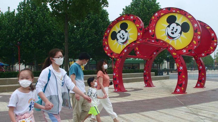 Visitors, wearing face masks, wait to enter the Disneyland theme park in Shanghai as it reopened, Monday, May 11, 2020. Visits will be limited initially and must be booked in advance, and the company said it will increase cleaning and require social distancing in lines for the various attractions. With warmer weather and new coronavirus cases and deaths falling to near-zero, China has been reopening tourist sites such as the Great Wall and the Forbidden City palace complex in Beijing.(AP Photo/Sam McNeil)