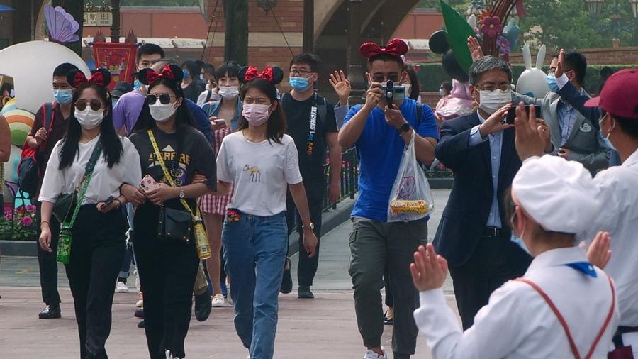 Visitors, wearing face masks, wait to enter the Disneyland theme park in Shanghai as it reopened, Monday, May 11, 2020. Visits will be limited initially and must be booked in advance, and the company said it will increase cleaning and require social distancing in lines for the various attractions. With warmer weather and new coronavirus cases and deaths falling to near-zero, China has been reopening tourist sites such as the Great Wall and the Forbidden City palace complex in Beijing.(AP Photo/Sam McNeil)